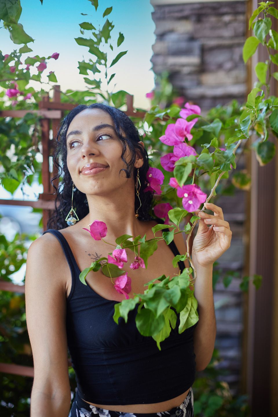 Ariana Hurtado, HypnoBirthing educator, smiling among pink bougainvillea