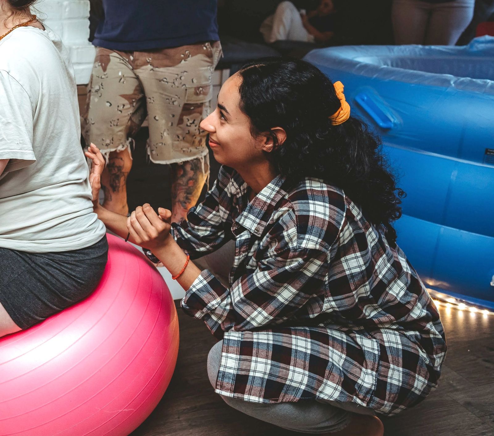 Ariana supporting a laboring mother on a birth ball beside a birth pool